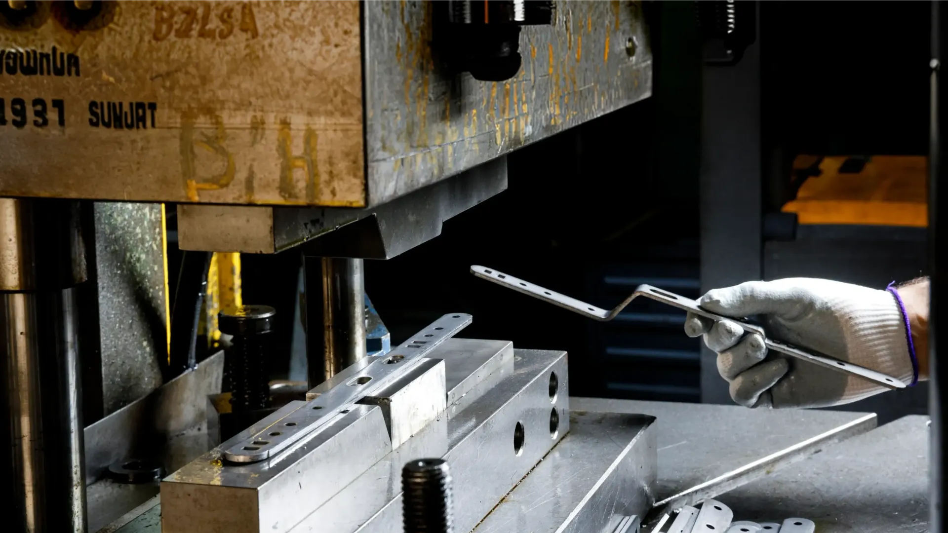 Mitarbeiter entnimmt einen gelochten Halter aus der Presse, ein Schritt im Prozess der Metallbearbeitung bei Sifral